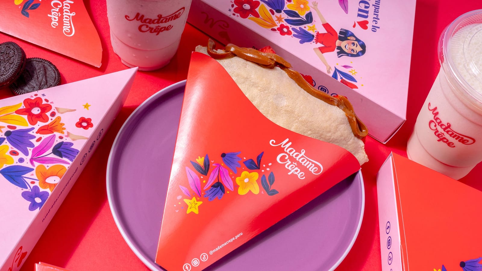 Crêpe de Madame en su cono floral, servido en un plato morado junto a su caja y un shake